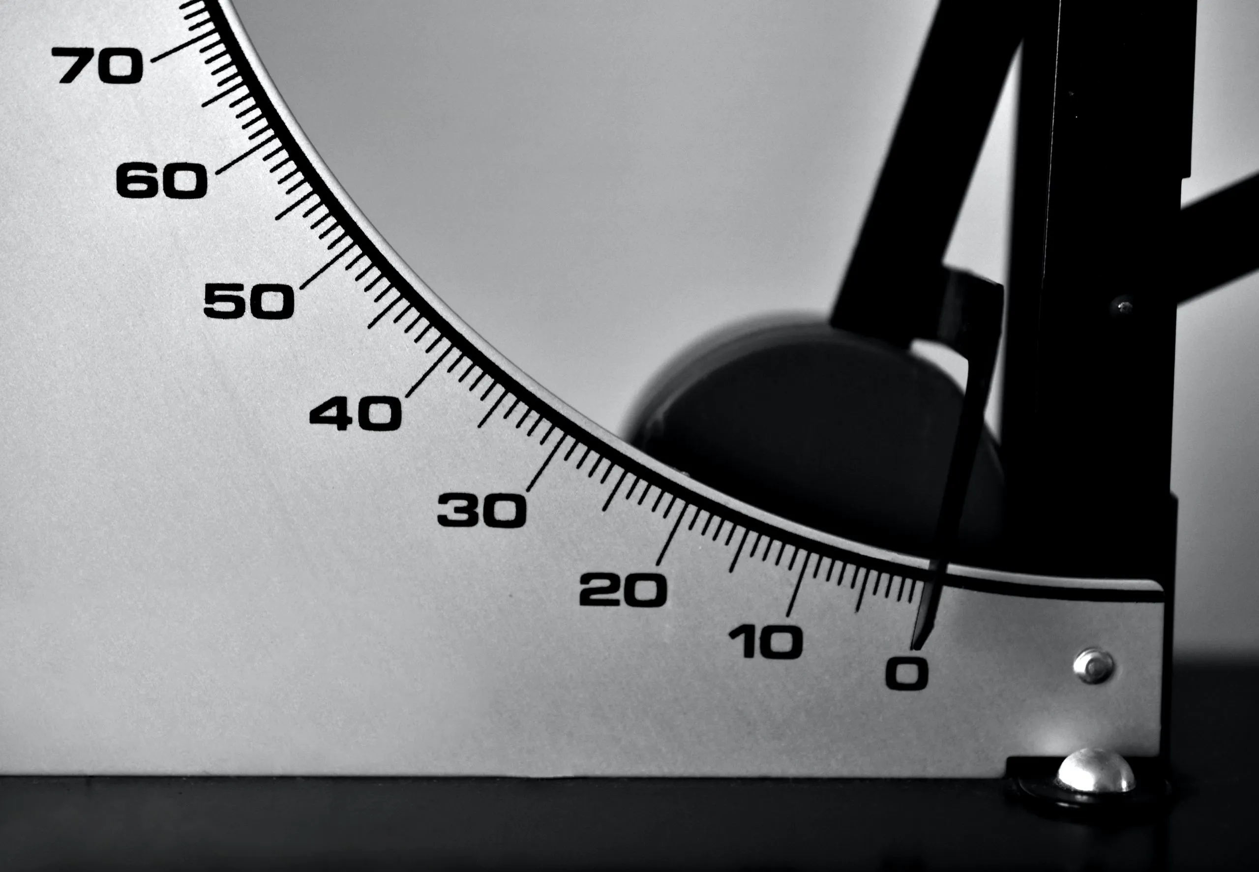 Close-up of a black-and-white measuring gauge with a curved numbered scale from 0 to 70 and a pointer near zero