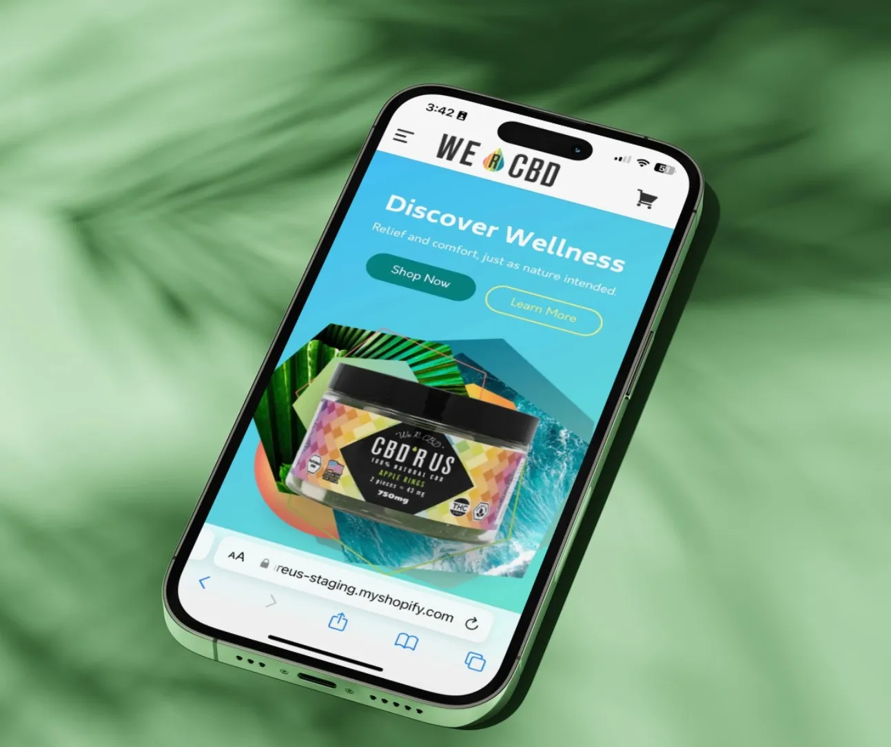 Phone showing the We R CBD mobile storefront with a 'Discover Wellness' hero and a CBD Apple Rings gummies product jar