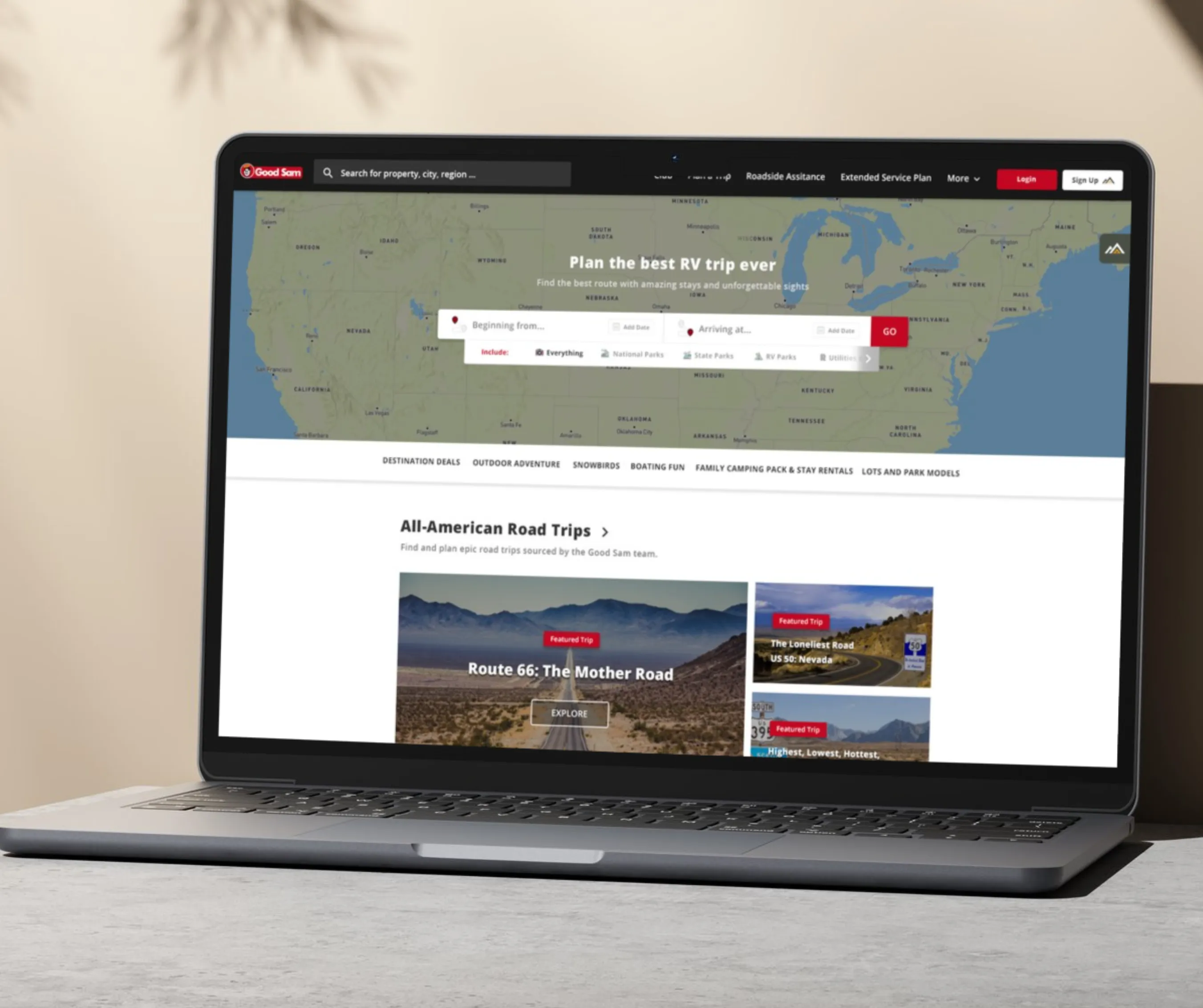 Laptop showing Good Sam RV trip planner homepage with a US map search and All-American Road Trips listings