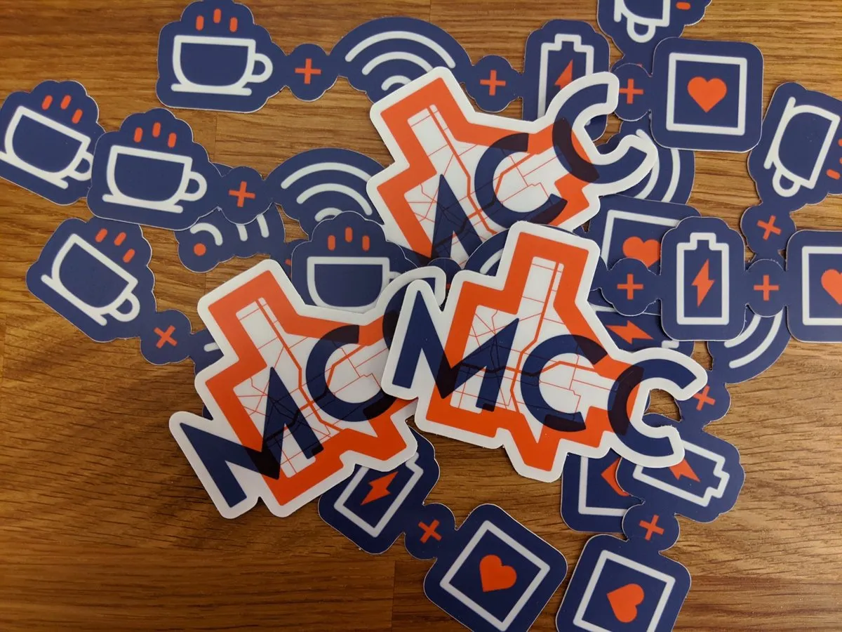Pile of MCC branded die-cut stickers — map-mark monograms and coffee, wifi, battery and heart icons