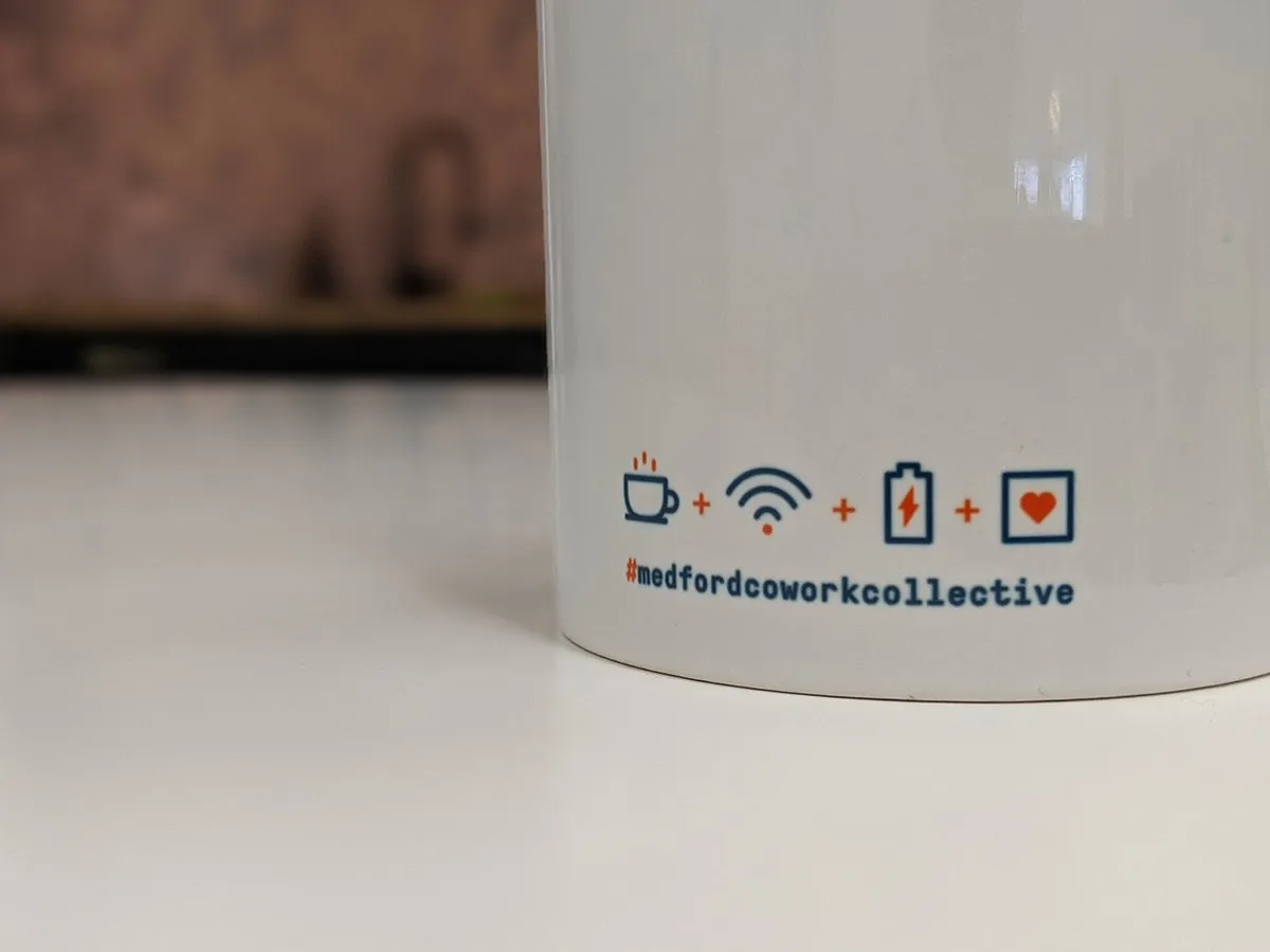 Reverse of the MCC mug showing the coffee-wifi-battery-heart icon row above '#medfordcoworkcollective'