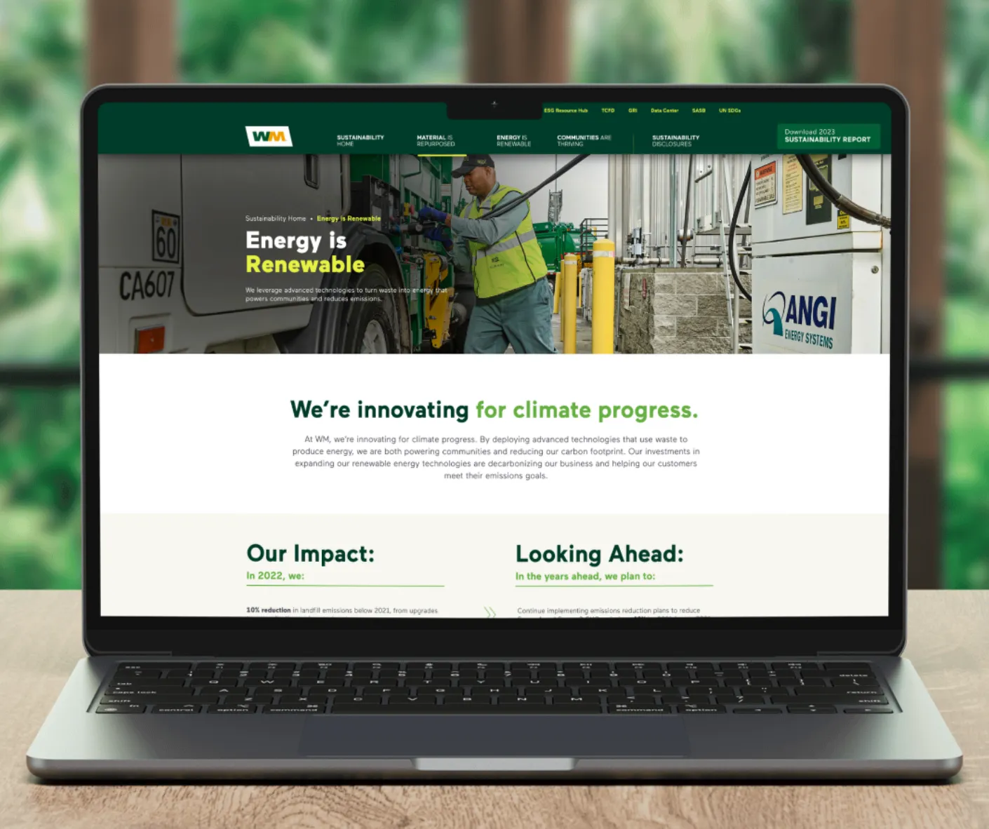 Laptop mockup of WM 'Energy is Renewable' page showing a worker at a renewable natural gas facility with impact metrics
