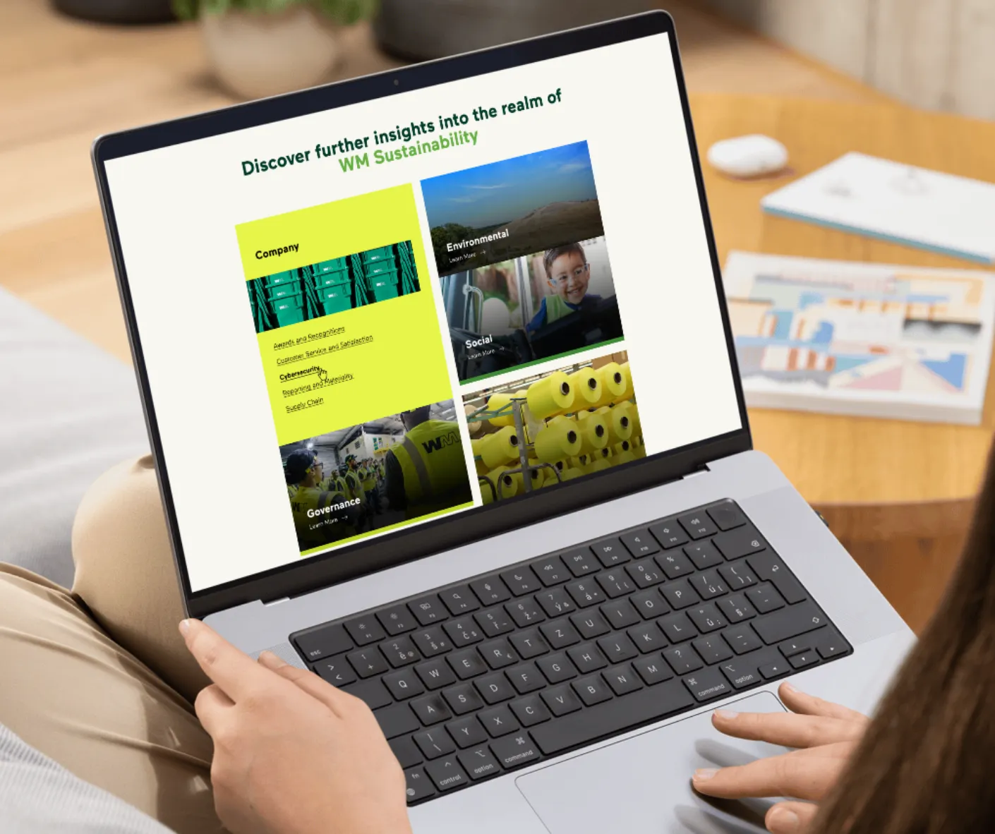 Person holding a laptop showing WM Sustainability insights page with Company, Environmental, Social and Governance topic tiles