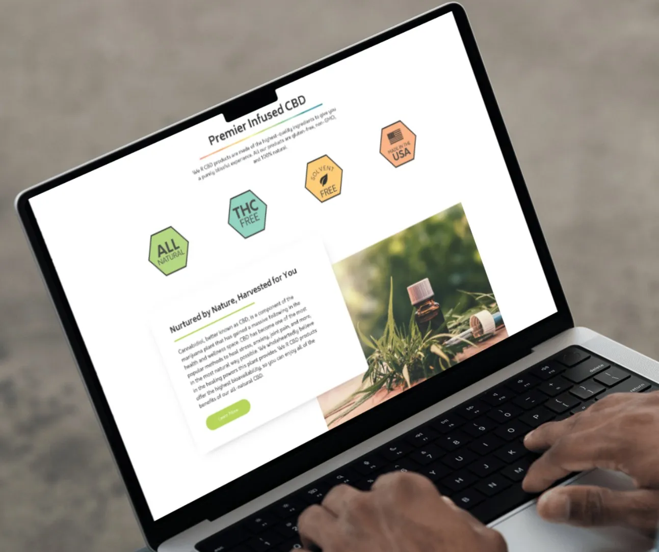 Laptop showing a We R CBD page with All Natural, THC Free, Solvent Free and Made in USA badges and a 'Nurtured by Nature' section